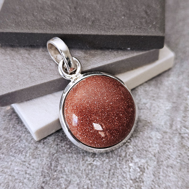 Silver pendant with a brown stone on a textured surface
