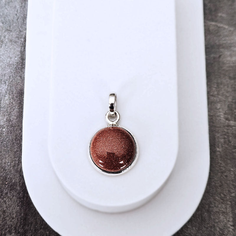Brown pendant on a white stand with a gray background