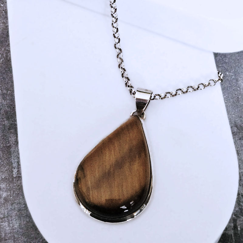 Tiger's eye teardrop pendant on a silver chain against a white background