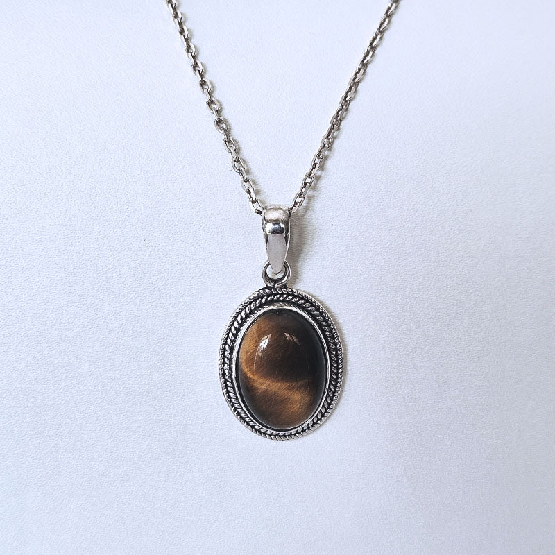 Silver chain necklace with an oval pendant featuring a brown tiger's eye stone in a textured silver bezel, shown on a plain light background.