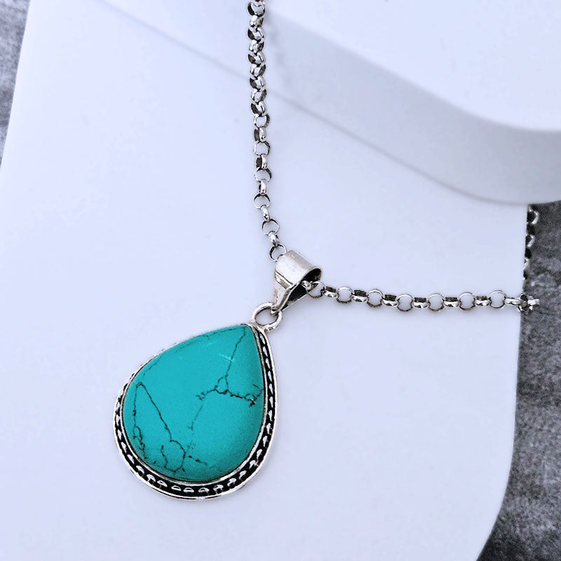Teardrop-shaped Turquoise pendant set in sterling silver on a white background