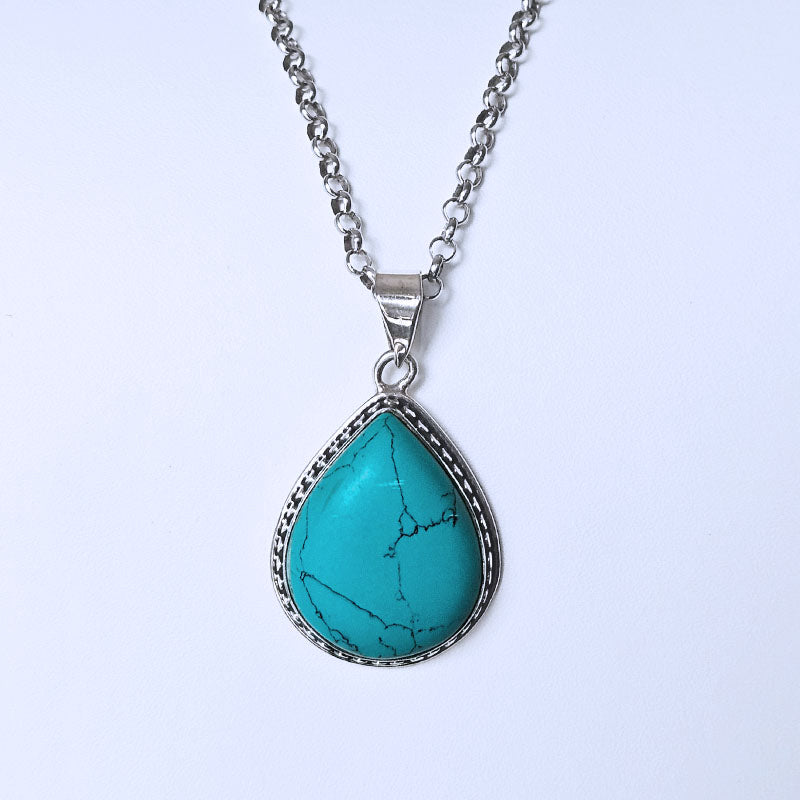 Teardrop-shaped Turquoise pendant set in sterling silver on a white background