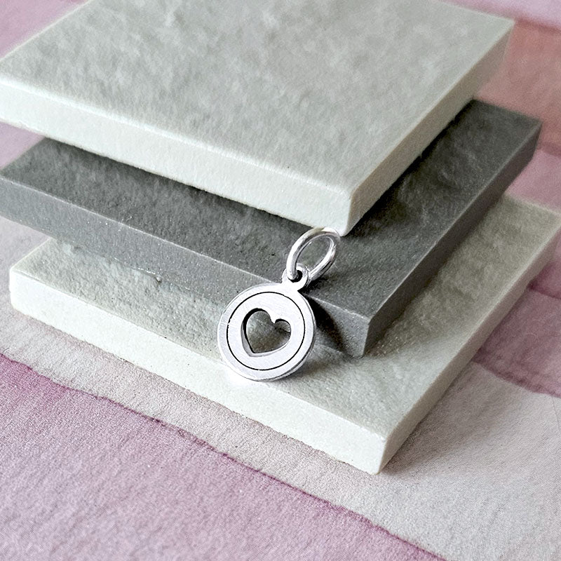 Silver pendant with heart design on a stone surface
