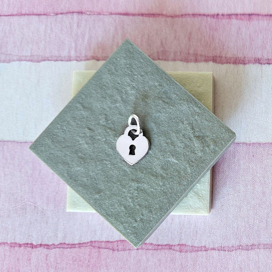 Silver lock-shaped charm on a green card with a pink and white striped background
