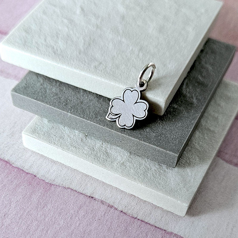 Silver flower-shaped pendant on a stack of gray and white stones