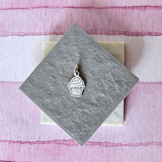 Silver cupcake charm on a gray card with a pink and white striped background