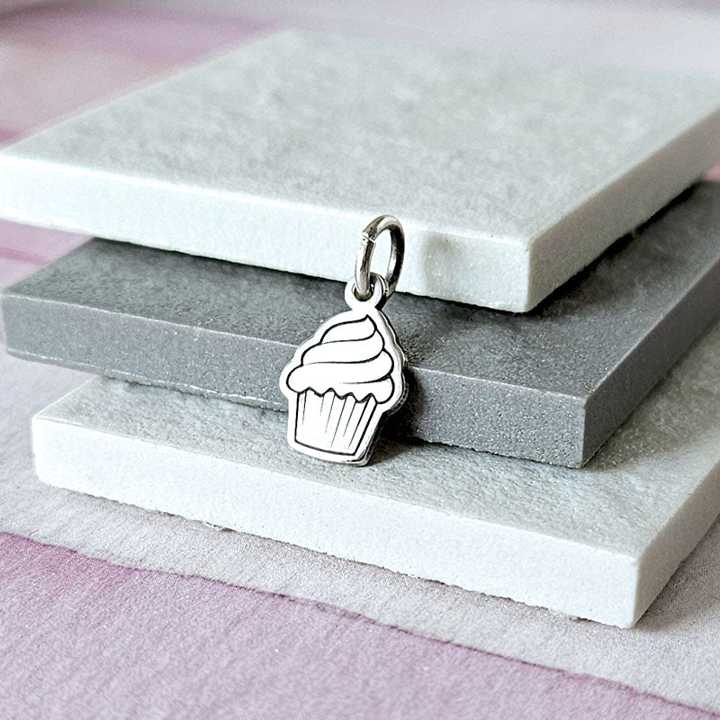 Silver cupcake charm on a stack of gray stone slabs