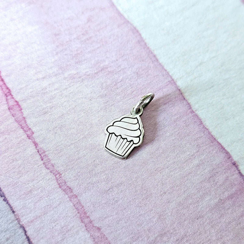 Silver cupcake charm on a pink fabric background