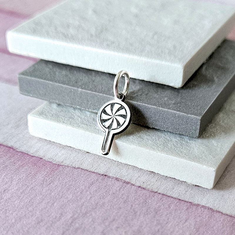 Silver swirl lollipop pendant on a stack of gray and white stones