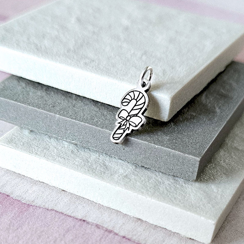 Silver candy cane charm on a stone surface