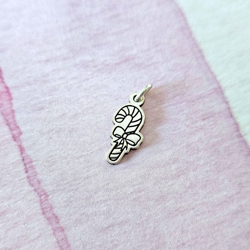 Silver candy cane charm on a pink fabric background