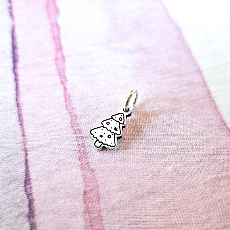 silver christmas tree charm on a pink background