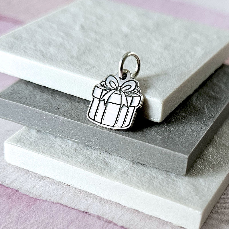 Silver gift box charm on a stone surface