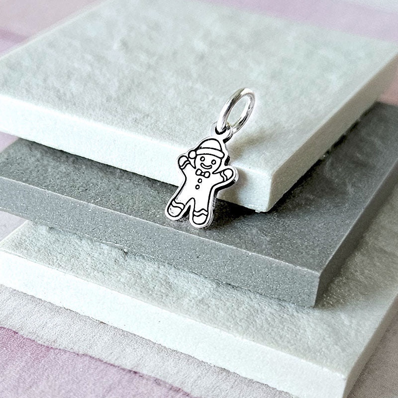 Silver gingerbread man charm on a stone surface