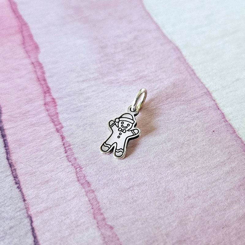 Silver gingerbread man charm on a pink fabric background