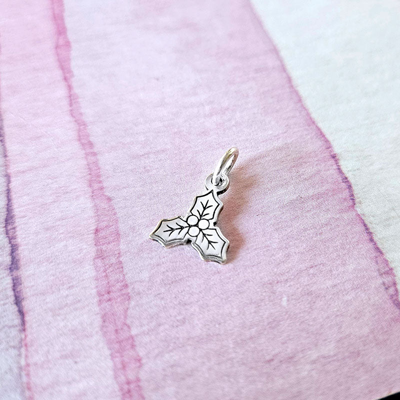 silver mistletoe charm on a pink fabric background