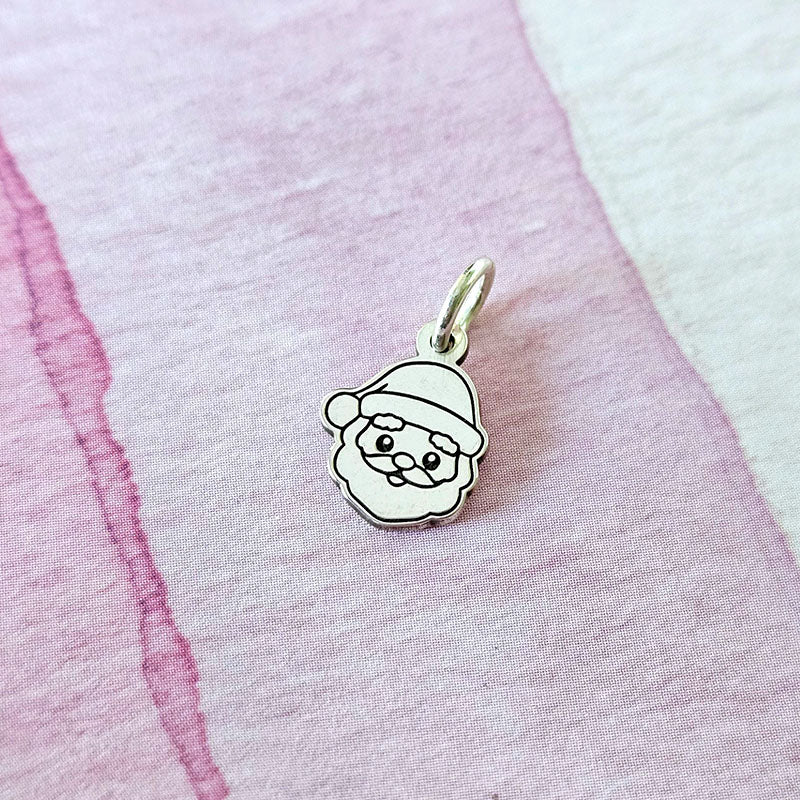 Silver pendant with a Santa Claus design on a pink fabric background