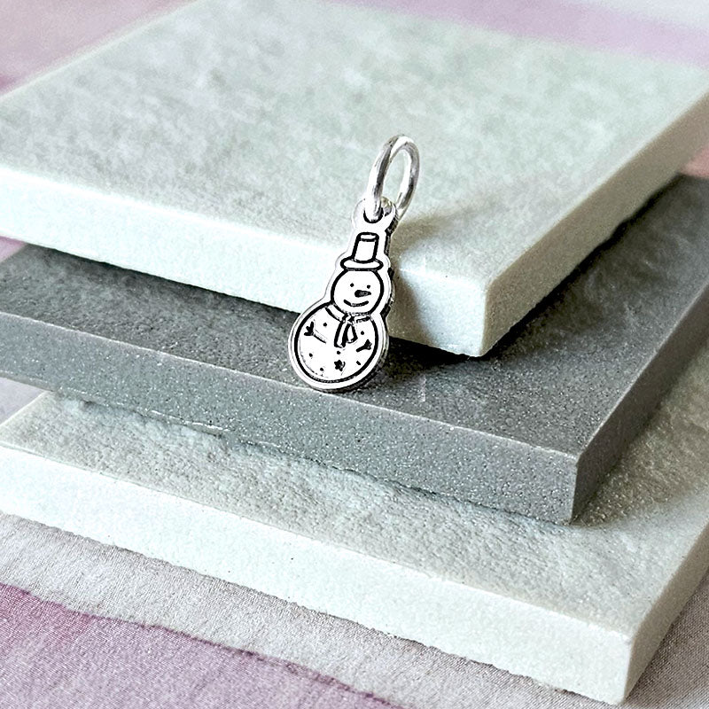 Silver snowman charm on a stack of stone slabs