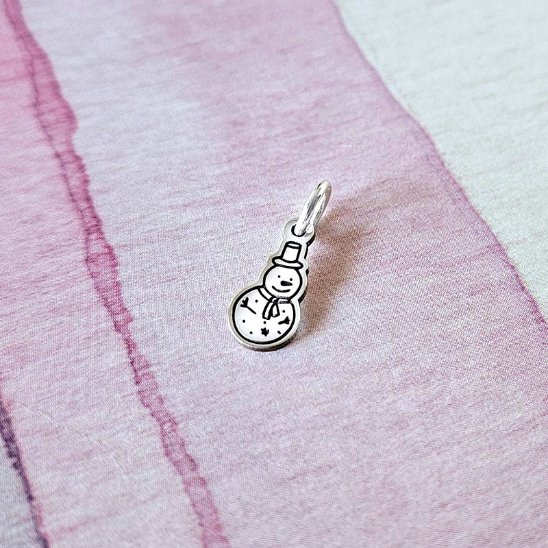 Silver snowman charm on a pink fabric background