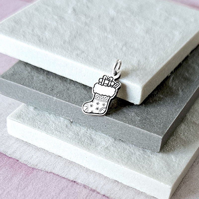 Silver stocking charm on a white stone surface