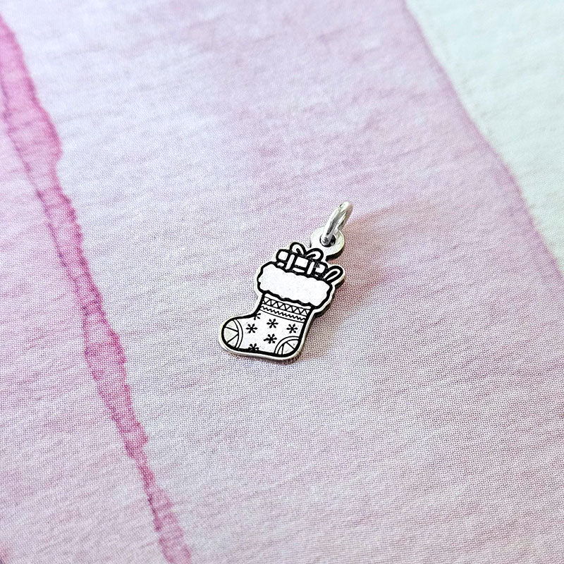 Silver stocking charm with presents on a pink fabric background
