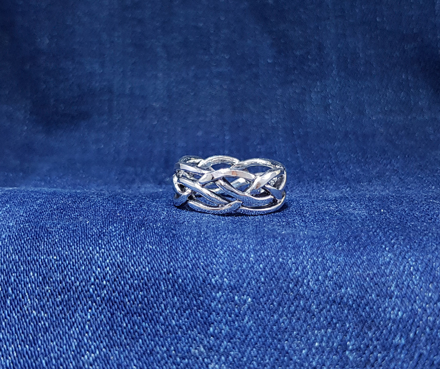 A broad Celtic weave ring displaying an intricate and interlacing pattern inspired by Celtic artistry.