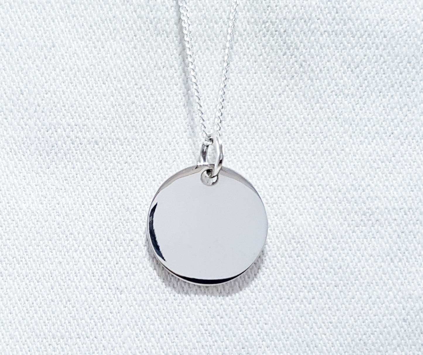 A medium-sized round disc pendant, simple yet stylish in design. The pendant features a smooth and polished circular shape, creating a clean and contemporary look. 